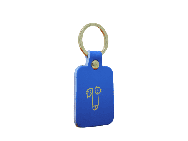 A rectangular red Dick Key Ring with a gold metal split ring, featuring a simple line drawing of a face on the front. Showcasing curated Estonian design against a plain white background. Gate21.ee
