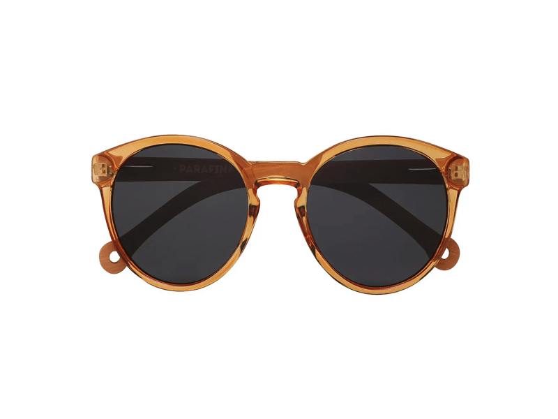 The "Costa" Caramel Sunglasses feature round, amber-tinted transparent frames and dark lenses, displayed on a white background—an ideal curated accessory for any gift shop. Gate21.ee