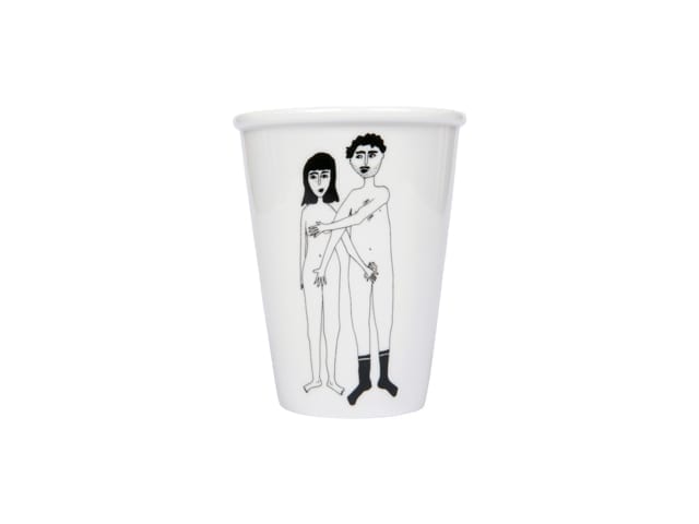 The Couple Cup - Front is a white mug from a concept shop, featuring a black line drawing of a nude man (in socks, arm around the long-haired woman) and woman standing side by side—a unique gift shop addition. Gate21.ee