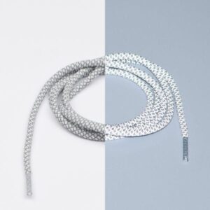 A white shoelace with a black pattern is arranged in a spiral shape. The background is split vertically, with the left side white and the right side light grey—an example of minimalist Estonian design perfect for Tallinn shopping or a unique gift shop find. Gate21.ee