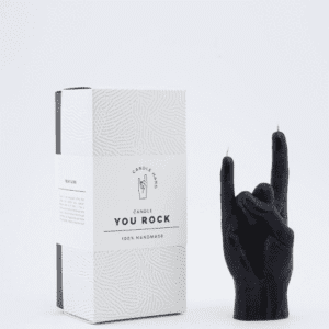 A black hand-shaped "Let's Rock - Black" candle, making the rock-on gesture, stands beside a white CandleHand box with subtle textures—ideal for concept shops seeking unique, curated products. Gate21.ee