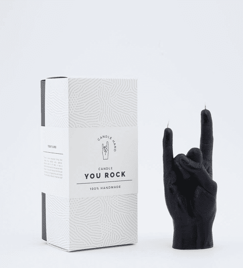 A black hand-shaped "Let's Rock - Black" candle, making the rock-on gesture, stands beside a white CandleHand box with subtle textures—ideal for concept shops seeking unique, curated products. Gate21.ee
