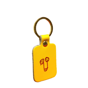 The Dick Key Ring - Red is a yellow rectangular keyring with rounded edges, a metal ring, and a red line drawing of two faces flanking a central vertical shape—perfect for Tallinn shopping. Gate21.ee