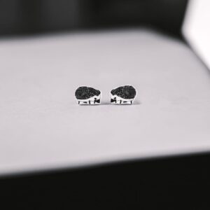 A pair of Siilid Kõrvarõngad, small silver hedgehog-shaped earrings crafted with curated Estonian design, rest on a light-coloured surface against a softly blurred background. Gate21.ee