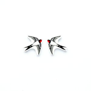 Two enamel badges shaped like swallows with black and white wings and red heads, positioned facing each other on a plain white background&mdash;a charming piece of Estonian design, perfect for any gift shop or concept store. Gate21.ee