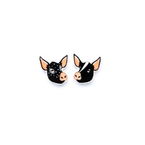 Two enamel pins shaped like pig faces on a white background. Featuring curated Estonian design, one pig has white spots and a circular pattern around an eye, whilst the other sports a solid black face with a white stripe down the middle. Gate21.ee