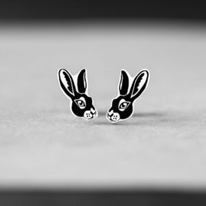 A pair of Siilid Kõrvarõngad—black and white earrings shaped like rabbit heads with prominent ears and minimalist faces—is displayed on a light surface, ideal for those seeking unique accessories in Tallinn. Gate21.ee