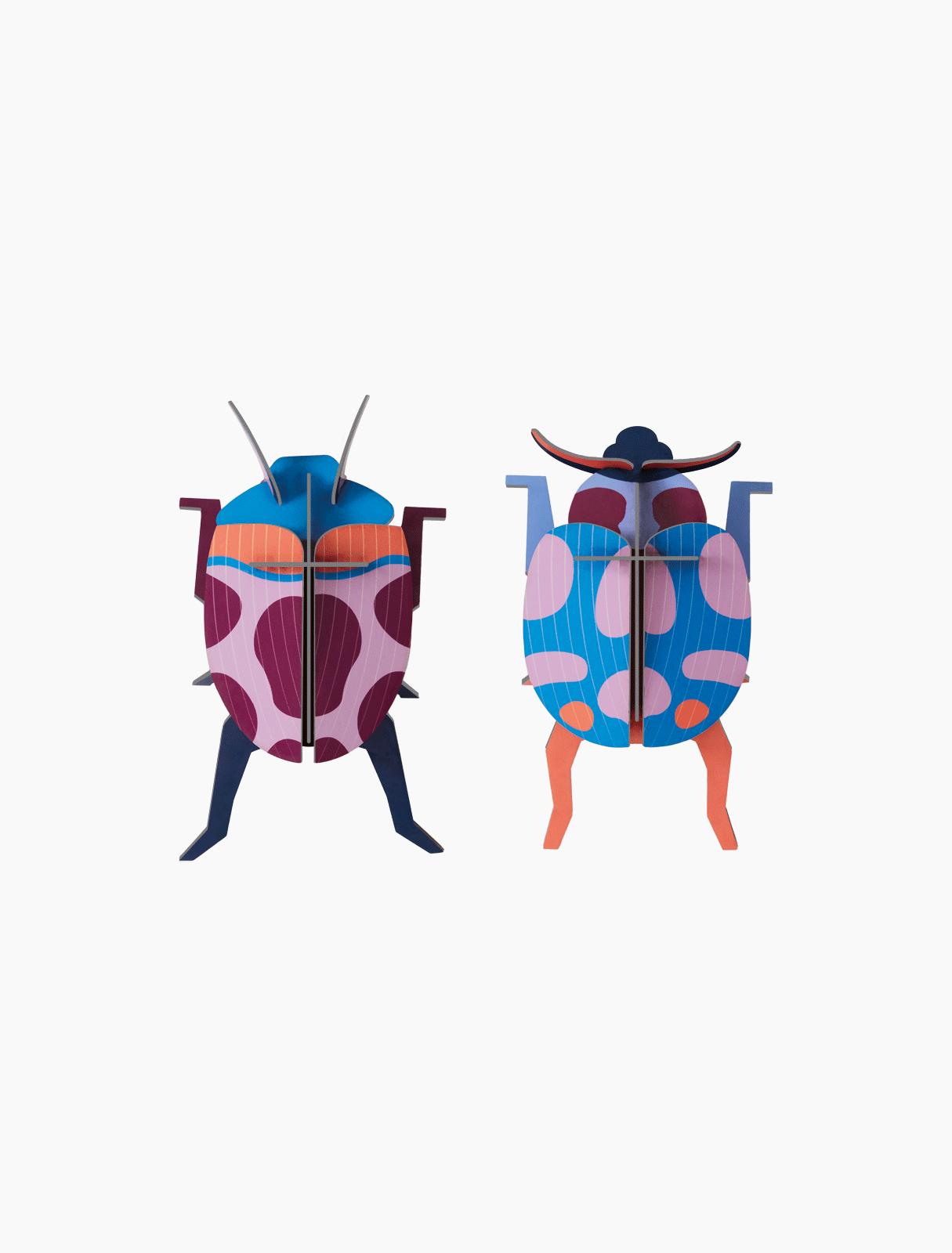 Coccinelle Couple features two vibrant beetle models crafted from flat, interlocking pieces. Celebrating Estonian design, each showcases bold geometric patterns in purple, blue, pink, and orange against a white background. Gate21.ee