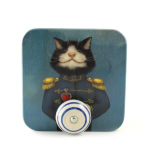 A square decorative piece featuring an illustration of a black and white cat in a blue military uniform with gold accents and a red heart, perfect for Tallinn shopping or adding unique Estonian design flair to your home. Blue and white striped knob included. Gate21.ee