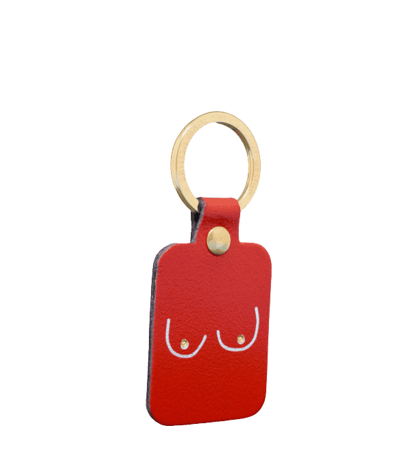 The Boob Key Ring - Red is a rectangular red leather keyring with a gold-coloured ring, featuring a minimalist white line drawing of two breasts—a bold accessory for fans of unique concept shop finds. Gate21.ee