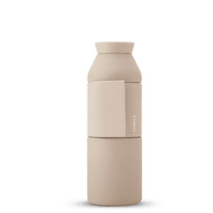 The Closca Wave - Sahara is a beige, cylindrical water bottle with a matte finish and a detachable cup section—ideal for unique gift ideas. "CLOSCA" is printed vertically on the side against a plain white background. Gate21.ee