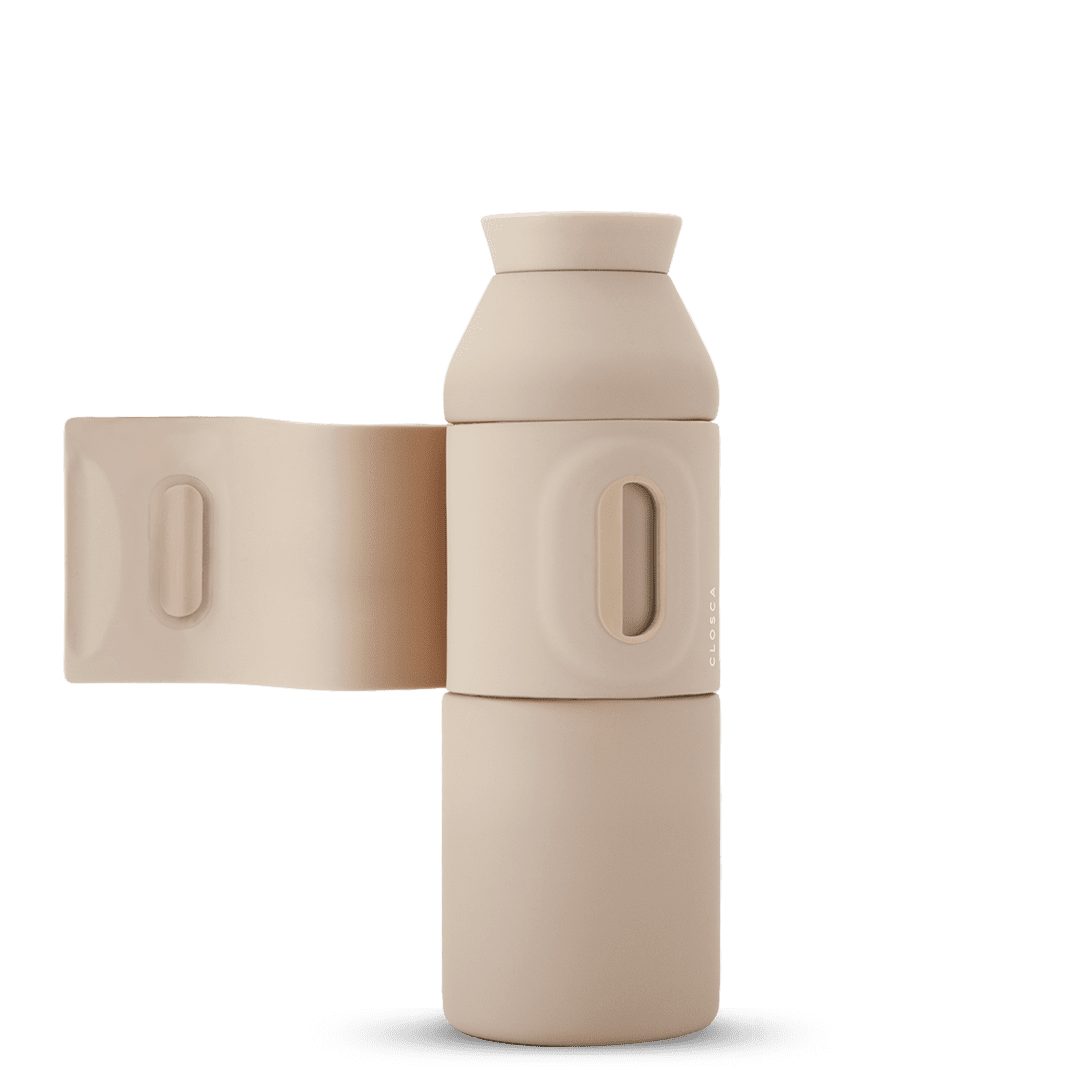 The Closca Wave - Sahara is a beige, matt-finish reusable water bottle with a wide mouth and folding side handle, standing upright against a white background—a stylish example of Estonian design ideal for gift shops. Gate21.ee