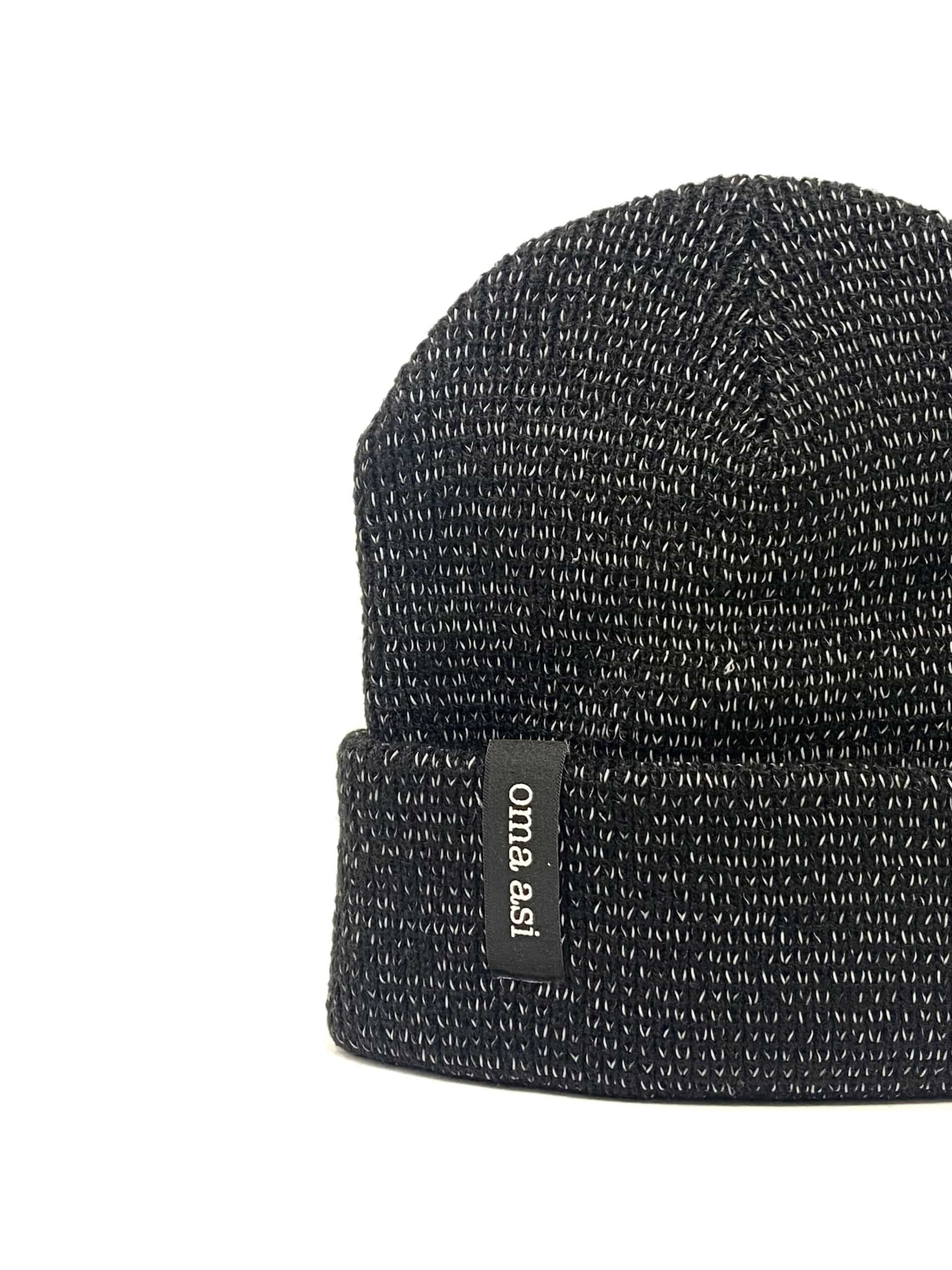 The Reflective Unisex Beanie - Black features a black and white knitted design with a turned-up brim, accented by a small black oma.asi tag—ideal as a standout gift from a Tallinn shopping destination. Shown against a white background. Gate21.ee