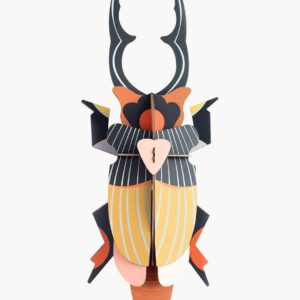 The Giant Stag Beetle is a vibrant 3D paper sculpture with striped wings and bold mandibles, featuring orange, yellow, black, and pink geometric shapes—an eye-catching Estonian design perfect for gift shops against a white background. Gate21.ee