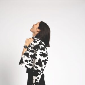 A person with shoulder-length dark hair stands sideways against a white background, smiling and holding the Black / Silver / 40mm—an eye-catching piece that reflects unique ideas inspired by Estonian design. Gate21.ee
