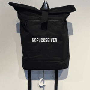 A black Roll-Top Rucksack hangs on a white hook, featuring bold white “NOFUCKSGIVEN” lettering—an edgy Estonian design perfect for making a statement, available at your favourite concept store. Gate21.ee