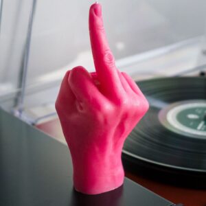 The F*ck You Candle – pink, shaped like a hand with an extended middle finger, sits beside a vinyl record player—a bold choice from a curated Tallinn gift shop. Gate21.ee