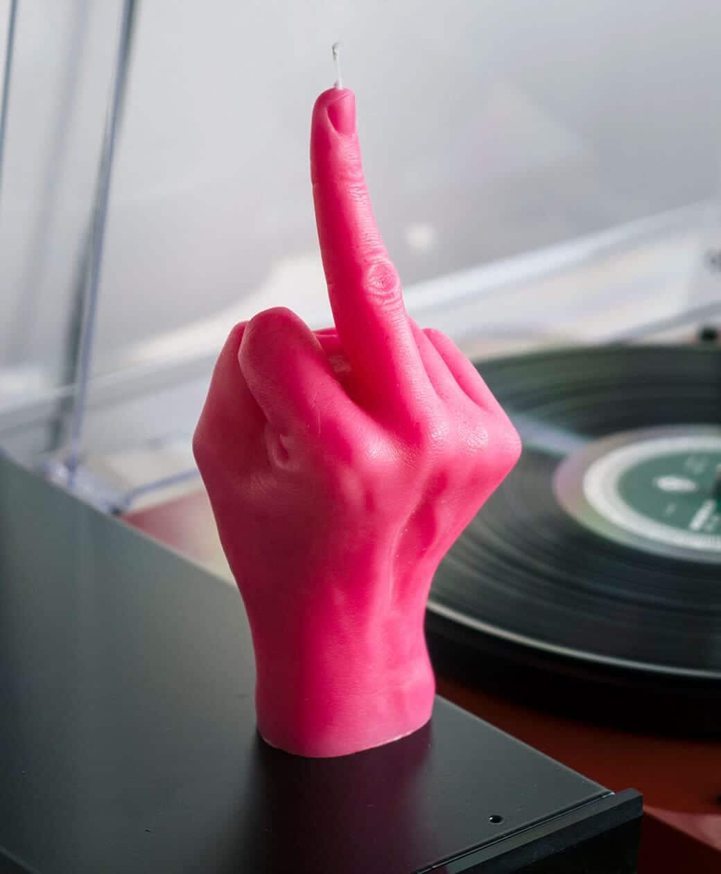 The F*ck You Candle – pink, shaped like a hand with an extended middle finger, sits beside a vinyl record player—a bold choice from a curated Tallinn gift shop. Gate21.ee