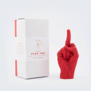 The F*ck You Candle - Red, shaped like a hand with the middle finger raised, sits next to its bold box—a handmade, edgy statement piece ideal for concept shops or those seeking unique finds in Tallinn. Gate21.ee
