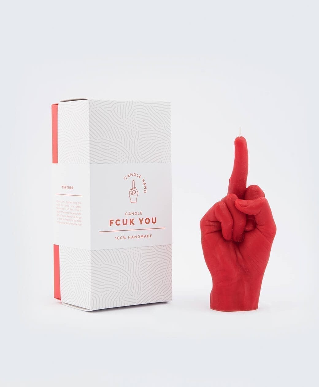 The F*ck You Candle - Red, shaped like a hand with the middle finger raised, sits next to its bold box—a handmade, edgy statement piece ideal for concept shops or those seeking unique finds in Tallinn. Gate21.ee