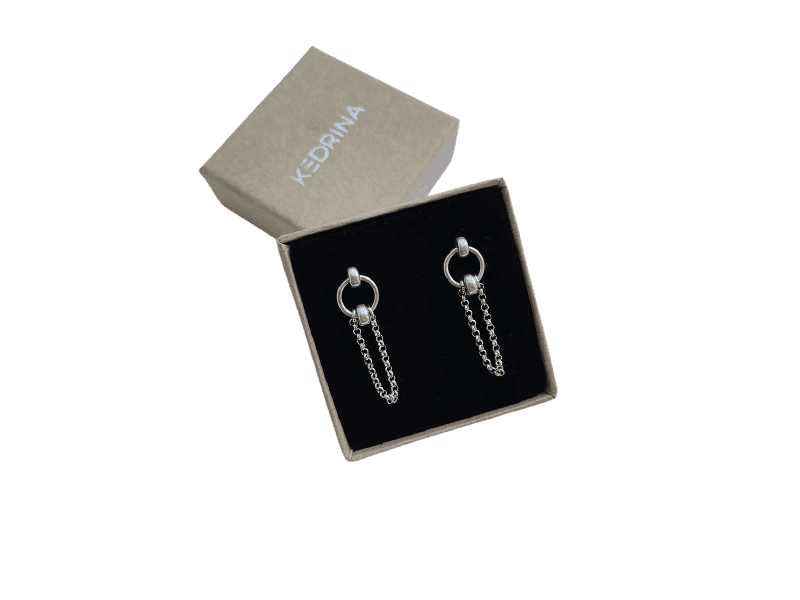 A pair of Insomnia - Small - Round Silver hoop earrings with double chain accents displayed in a black velvet-lined box, branded KEDRINA on the lid—a chic find from a Tallinn shopping concept shop. Gate21.ee