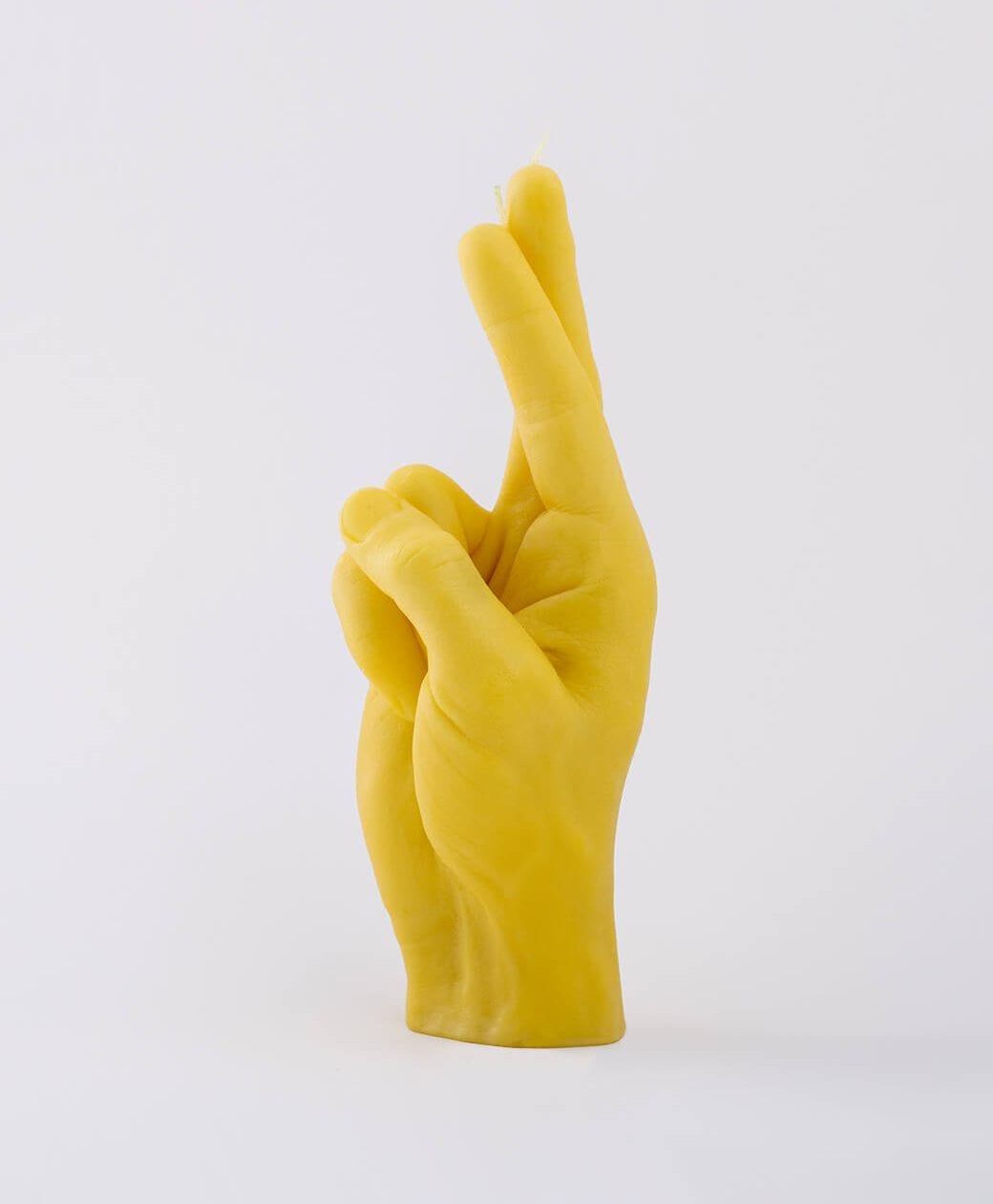 Fingers Crossed - Yellow: A unique Estonian-designed candle shaped like a yellow human hand with crossed index and middle fingers, shown on a plain white background. Gate21.ee