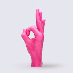 The OK – Pink candle, shaped like a human hand making an OK gesture, stands upright against a plain light grey background, showcasing curated Estonian design. Gate21.ee