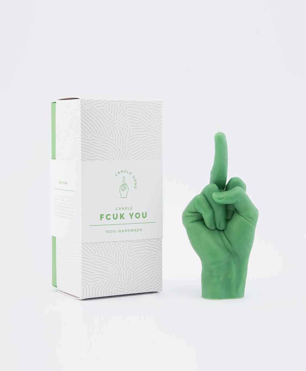 The F*ck You Candle - Green, shaped as a hand giving the middle finger, sits by its FCUK YOU box. This bold Estonian design stands out against a white backdrop—an ideal choice for your curated Tallinn shopping finds. Gate21.ee