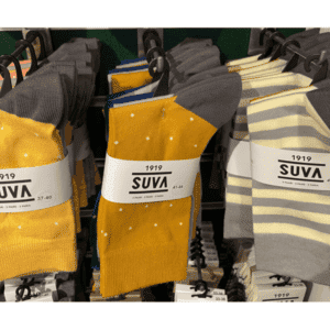 The 3pk Sokid - SUVA socks, featuring Estonian design with yellow, grey, and white polka dots and stripes, are displayed on hangers&mdash;making them a stylish choice for gift shops or Tallinn shoppers. Gate21.ee