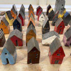 A curated set of Tass nagu + others by KAURI KALLAS features small ceramic houses in assorted colours and patterns, arranged neatly on wood&mdash;ideal for gift shop displays or creative d&eacute;cor ideas. Gate21.ee