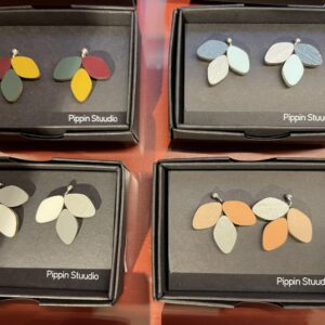 Four pairs of PIPPIN BIRD earrings in vibrant colours are displayed in black Pippin Stuudio boxes, highlighting unique Estonian design&mdash;ideal for Tallinn shoppers or those hunting for treasures in a concept shop. Gate21.ee