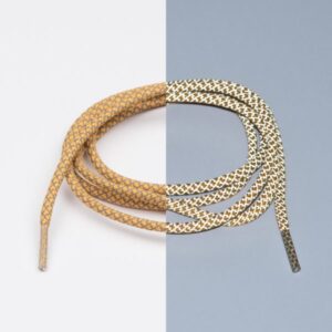 Reflective Rusty Laces - Extrawize are coiled on a vertically split white and grey background, blending tan, gold, black, and white tones in a modern Estonian-inspired style reminiscent of concept shops or gift shops. Gate21.ee