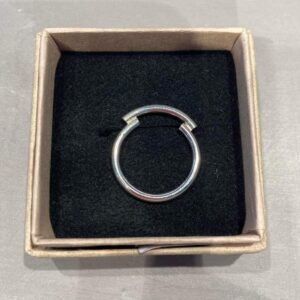 A silver circular ring with a small gap sits on a black velvet insert inside a square cardboard box. Perfect for those who love curated pieces, this ring is a standout choice found in Tallinn shopping or any trendsetting concept shop. Gate21.ee