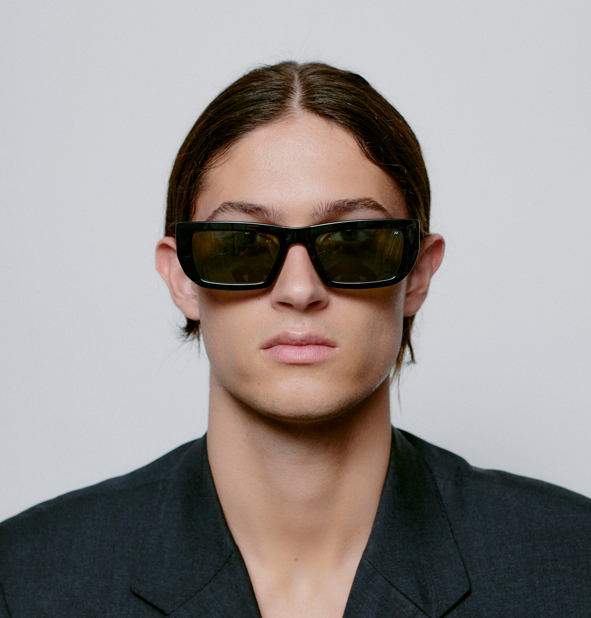 Wearing FAME - Black rectangular sunglasses and a dark blazer, a person with straight brown hair faces forward against a light grey background—showcasing the sleek, curated style of modern concept shops. Gate21.ee