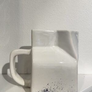 The SPLASH creamer - S is a white ceramic mug with square sides, a dented top left corner, and black splatters near the base&mdash;an eye-catching find for modern homes, ideal to discover at a Tallinn shopping concept shop. Gate21.ee
