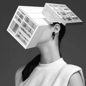 A woman in a sleeveless top with her head replaced by a geometric architectural form evokes the innovative style of Tallinn concept shops. She wears the DUALITY EARRINGS - DOUBLE in this striking black and white image. Gate21.ee