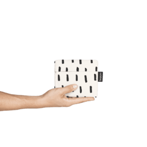 A hand holds the Black Brush pouch, featuring a black dashed line pattern and a black side tag, highlighting curated Estonian design against a plain white background. Gate21.ee