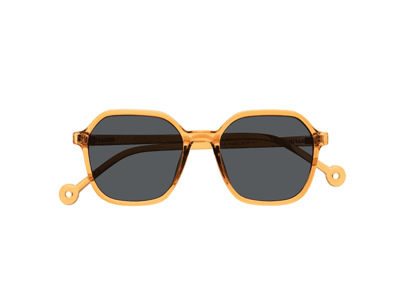 The "Valle" Caramel Sunglasses feature a translucent amber-coloured frame, geometric dark-tinted lenses, and unique circular detail at the temple tips—ideal for picking up at a Tallinn shopping concept store. Gate21.ee