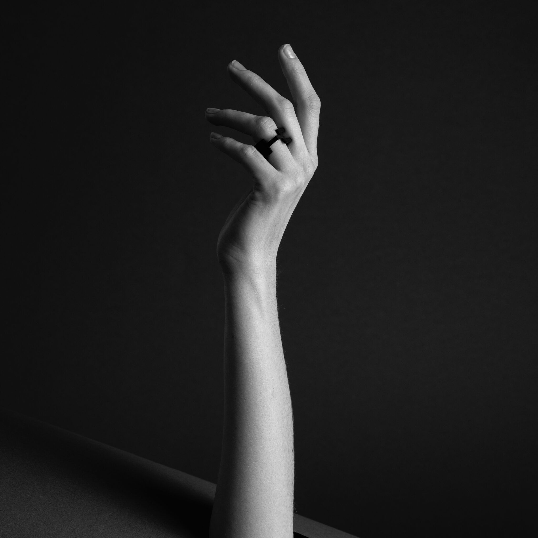 A single hand rises against a dark background, fingers gently curled, showcasing the DUALITY RING - KIMURA on the middle finger. Dramatic lighting highlights its elegant design, reflecting Tallinn shopping and unique local finds. Gate21.ee
