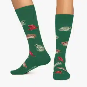 A person wears Frogs - Regular green socks with a colourful frog pattern, featuring NO TAMMY LION text visible near the toes on one sock, curated for unique style. Gate21.ee