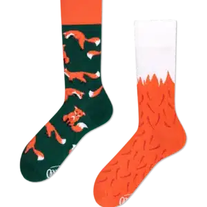 Two mismatched crew socks on a black background; one green with orange fox patterns, the other orange with a white top and carrot-like designs—perfect for those seeking unique ideas or inspired by playful Estonian design. Gate21.ee