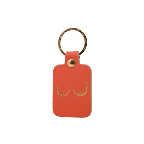 The Boob Key Ring - Coral is a rectangular orange leather keyring with a gold ring and an embossed line drawing of breasts—an Estonian-designed gift, ideal for those seeking something unique. Gate21.ee