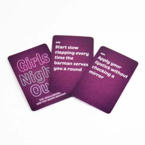 Three purple cards from the Girls' Night Out - Card Game are shown: one reads "Girls' Night Out," the second, "Start slow clapping every time the barman serves you a round," and the third, "Apply lipstick without checking a mirror. Gate21.ee