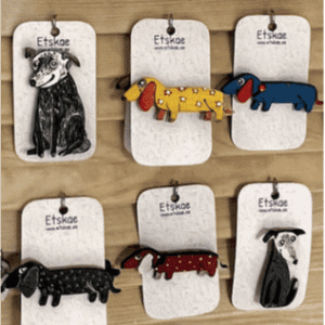 Six ETSKAE brooches - K&Otilde;IK, each with unique colours and designs, are displayed on cards attached to a wall&mdash;an eye-catching collection for anyone seeking distinctive accessories at a concept shop. Gate21.ee