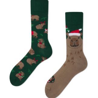 A pair of Merrybara socks: one green with capybaras in Santa hats and decorations, the other tan with a big capybara face in a Santa hat and holly, both with dark green cuffs. Gate21.ee