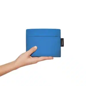 A hand holds "Blue," a rectangular blue fabric pouch with a black label featuring white text—an ideal choice from a curated Tallinn gift shop, set against a plain white background. Gate21.ee