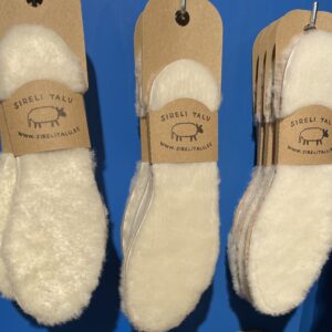 A set of Sheepskin Insoles - KÕIK from Sireli Talu, labelled with signature brown tags, is showcased against a blue background—ideal for concept shops or gift shops seeking unique display ideas. Gate21.ee