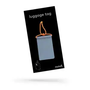 The Luggage Tag - Neon Orange features a grey tag with an orange loop, displayed on black packaging labelled "luggage tag." The packaging includes a suitcase outline and the word "march," making it ideal for curated gift shops or concept stores. Gate21.ee