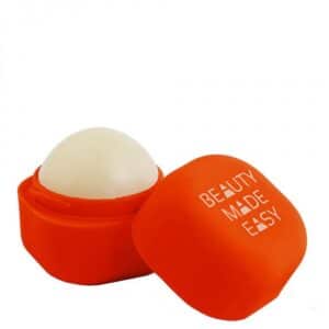 A spherical lip balm with a white dome sits in an open orange container. The detached lid beside it reads BEAUTY MADE EASY - LIPS - K&Otilde;IK in bold white capitals, showcasing curated Estonian design. Gate21.ee