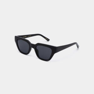The KAWS - Black features black square frames with dark lenses and thick arms, showcasing a minimalist Estonian design. Resting on a white surface, these modern sunglasses are an ideal addition to any gift shop collection. Gate21.ee